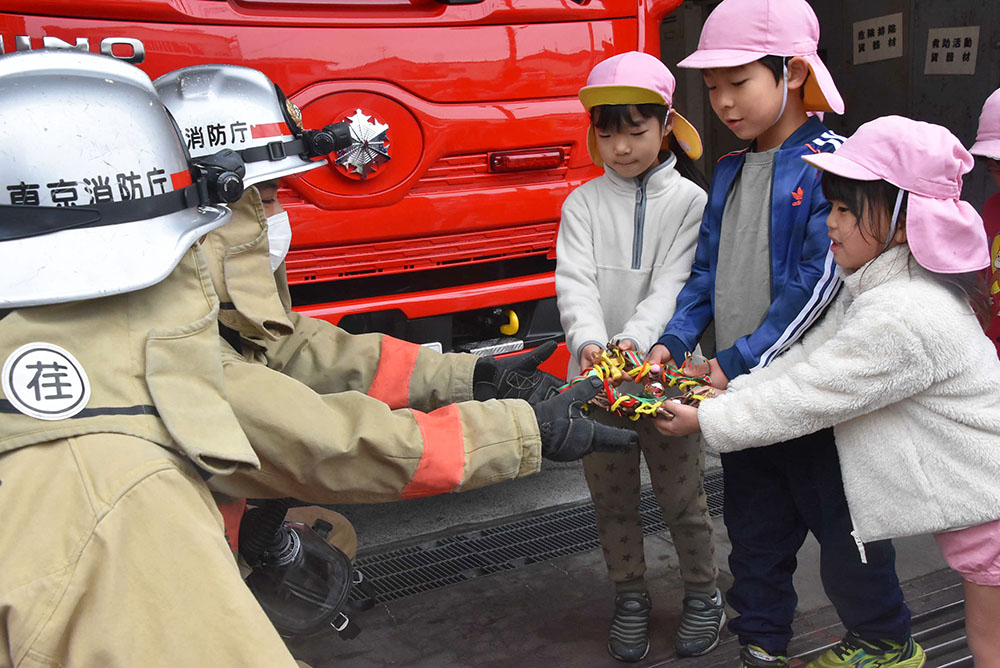 消防署職員へリースを渡す園児たち